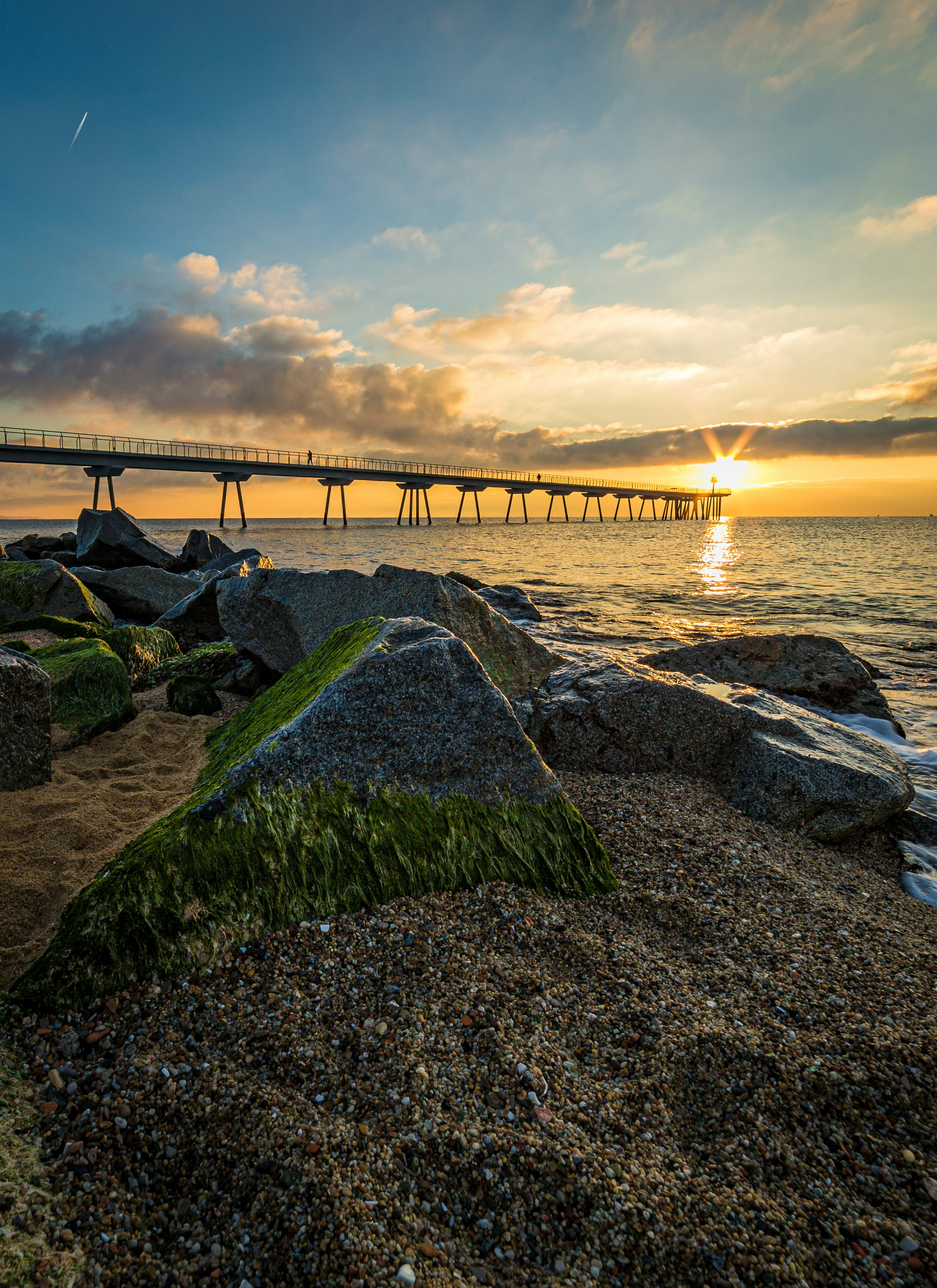 brown wooden bridge over the sea under white clouds